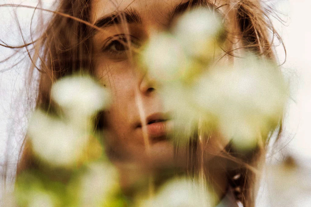 Close up of a woman's face behind flowers.