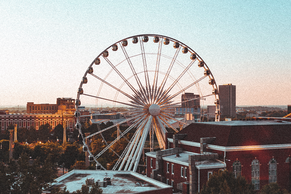 Ferris wheel in Georgia's skyline amidst buildings on a sunny day