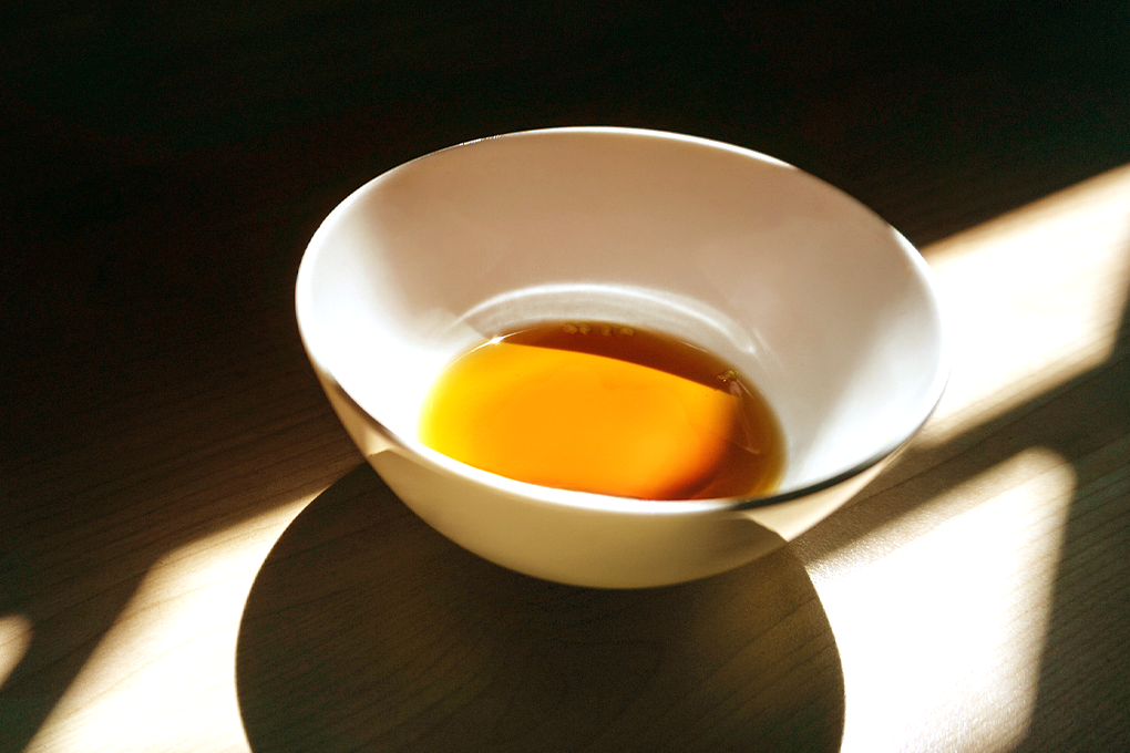 White bowl withs some yellow liquid oil product extract