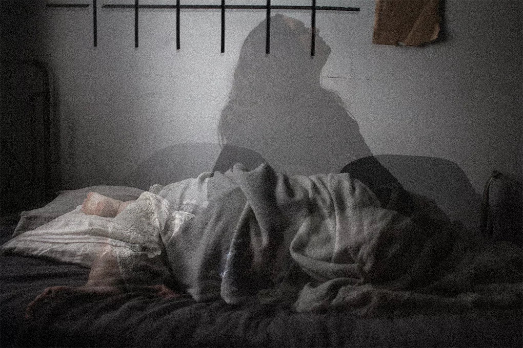An image of a person with their whole body under the covers as a shadow seems to push its way up through the covers signifying insomnia.