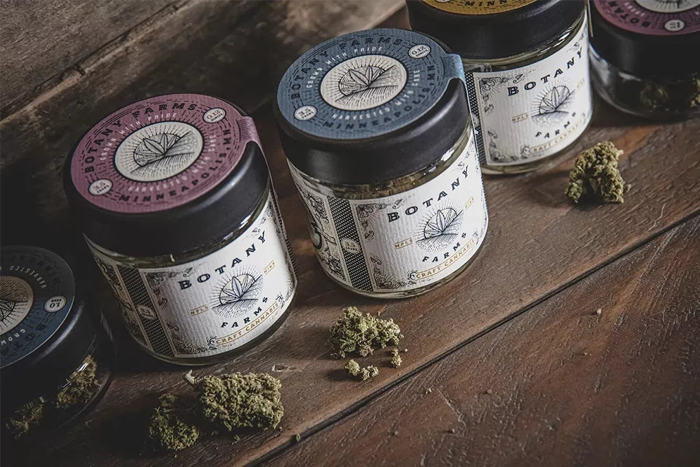A row of jars filled with Botany Farms flower sit on a wooden surface showcasing the best strains for weight loss