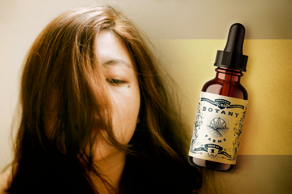 A dropper of Botany Farms tincture floats next to a woman with half her face covered by her hair. 