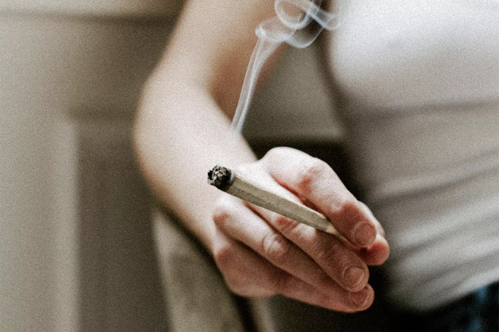 A close up of a heavy smoker's hand holding a smoking joint.