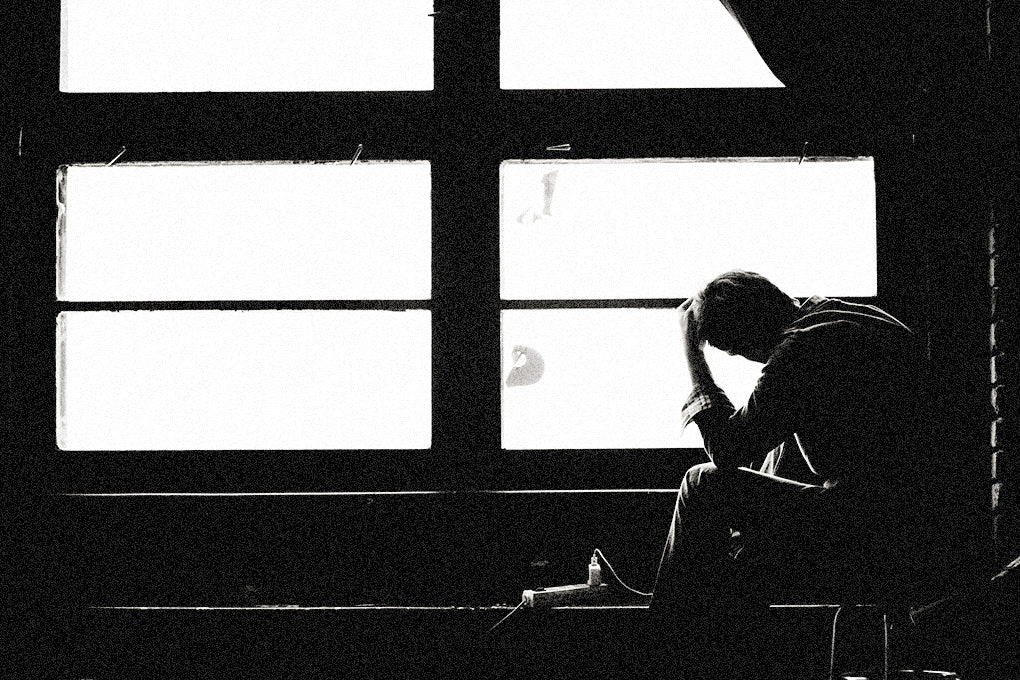 A black and white AI generated sketch of a man sitting in front of a window, head in hand, battling racing thoughts.