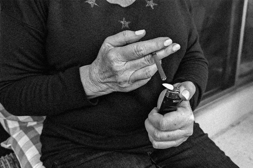 A black and white image of someone who appears to be a senior lighting a joint in their hands.