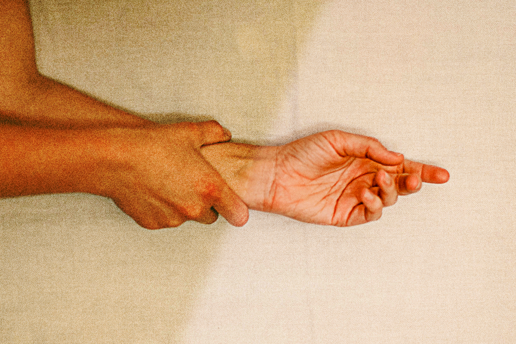 One man's hand is being clasped by another man's hand on a white surface