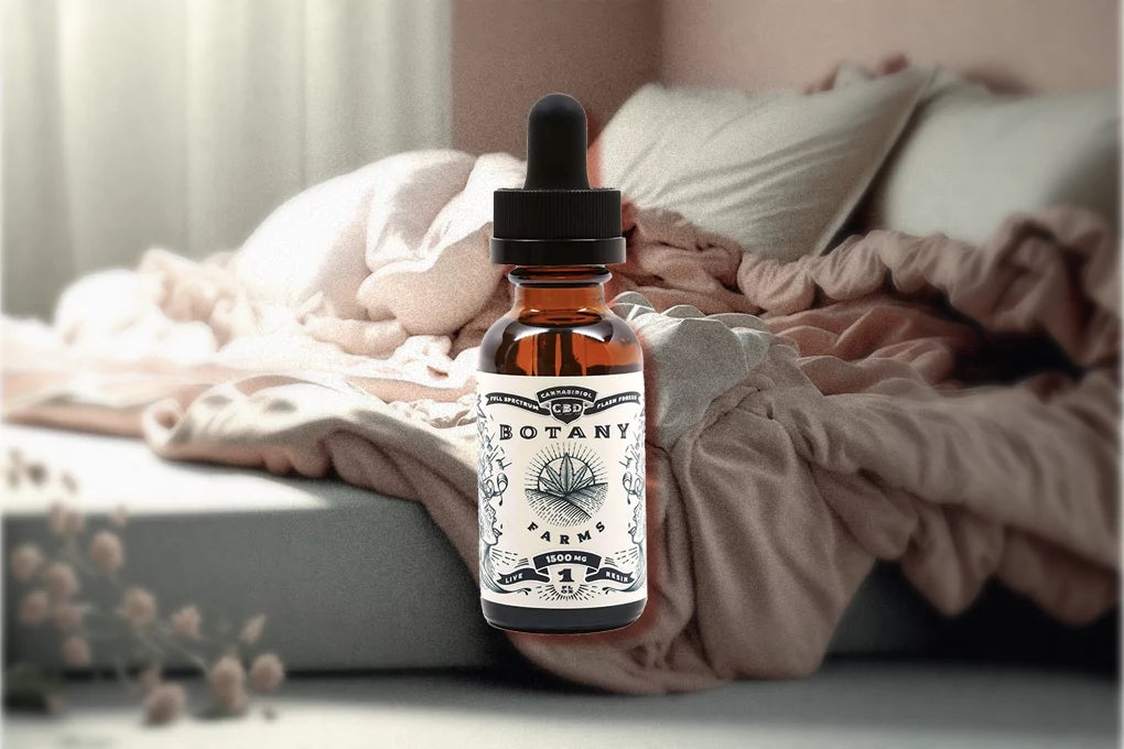 Botany Farms 1500mg live resin CBD oil tincture floats against a backdrop of a bed with pillows and blanket and flowers beside the bed