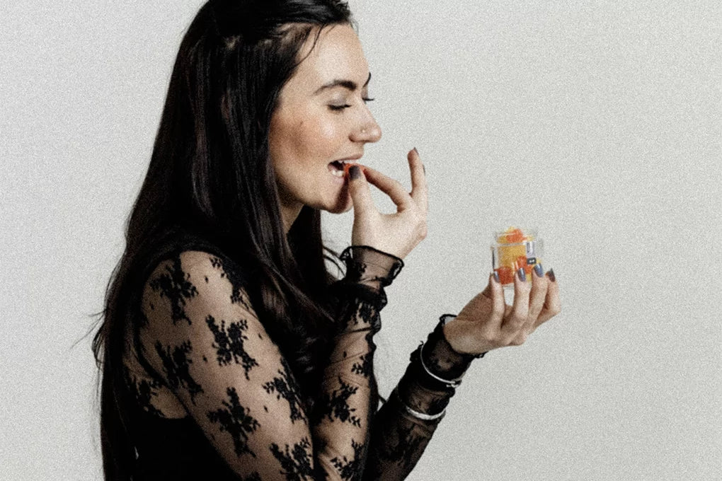 A woman is eating a CBD gummy out of a Botany Farms gummies jar.
