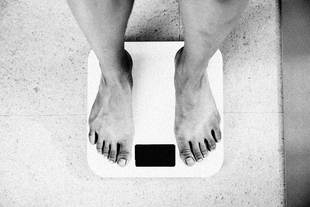 A view of a persons feet, looking down at a scale measuring their weight.