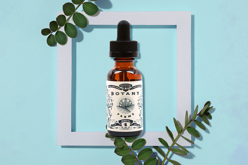 Botany Farms 1500mg CBD oil serum bottle set on light blue background with a white frame in the back and viagra leaves at the top and bottom