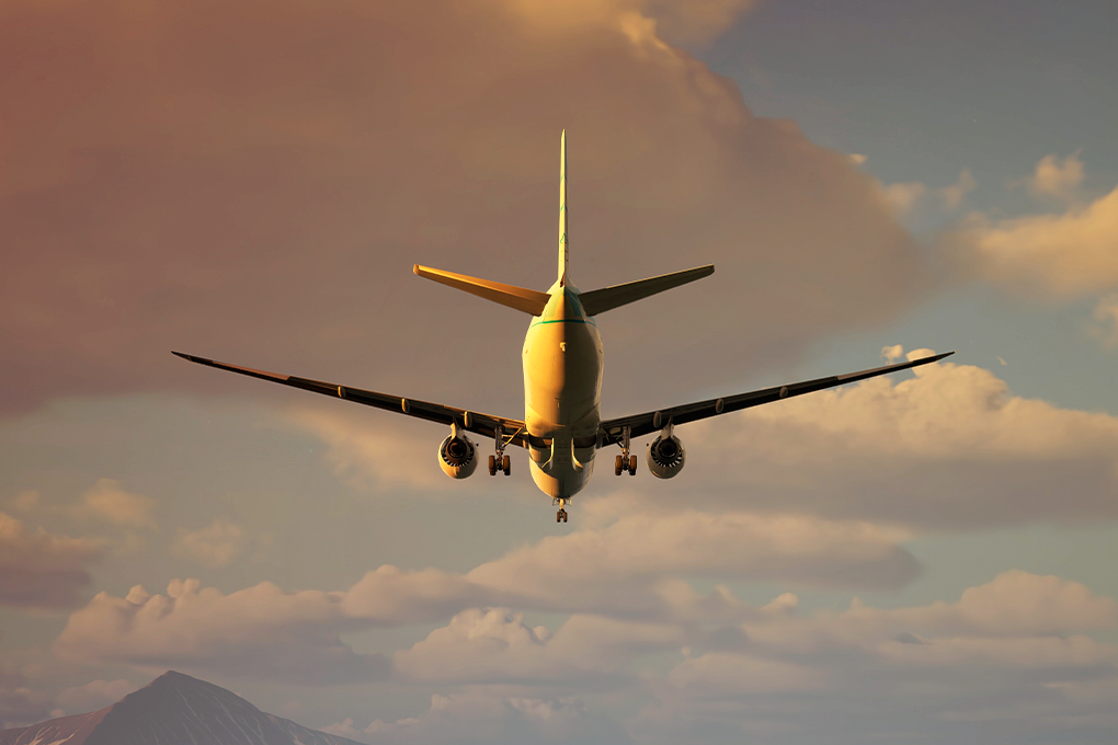 A plane flying in a blue sky with the red sun shining on its body