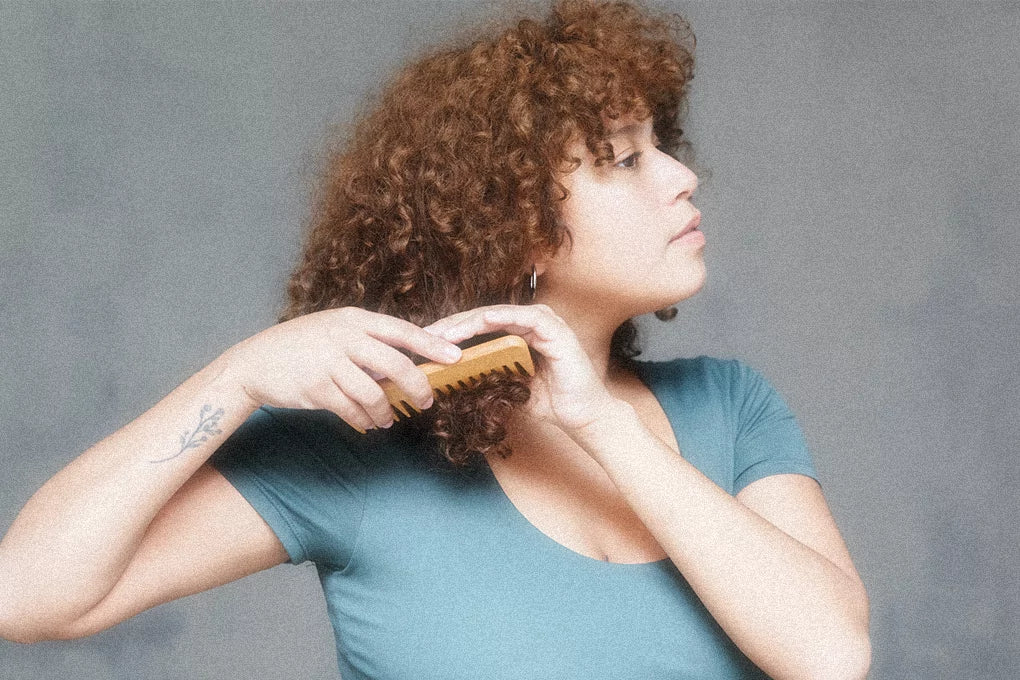 A woman combs her hair.