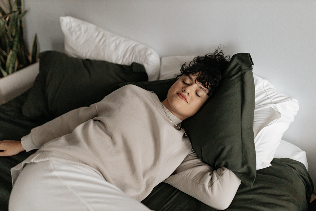 A top down image of a woman lying on a black and white bed and sleeping.