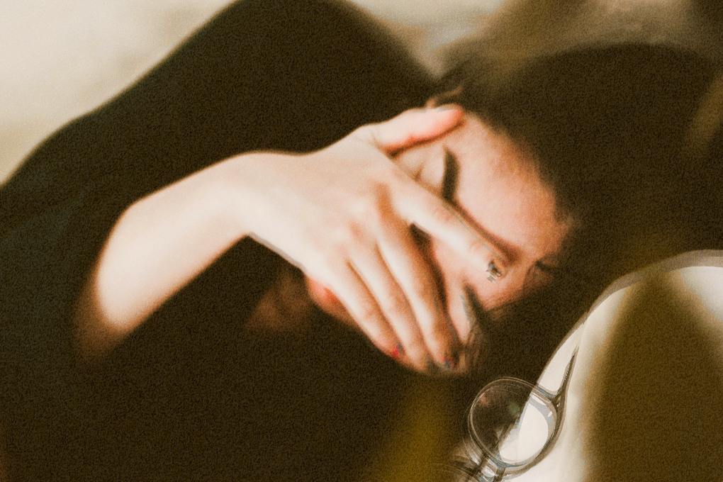 Relaxed woman sleeping peacefully, resting on a pillow, eyes closed, hand gently covering her face and eyes for added comfort