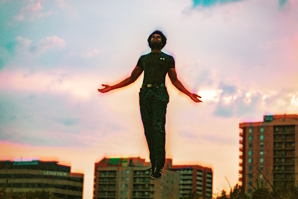Man experiencing euphoria, floating in mid-air against a blue sky backdrop with buildings in the background