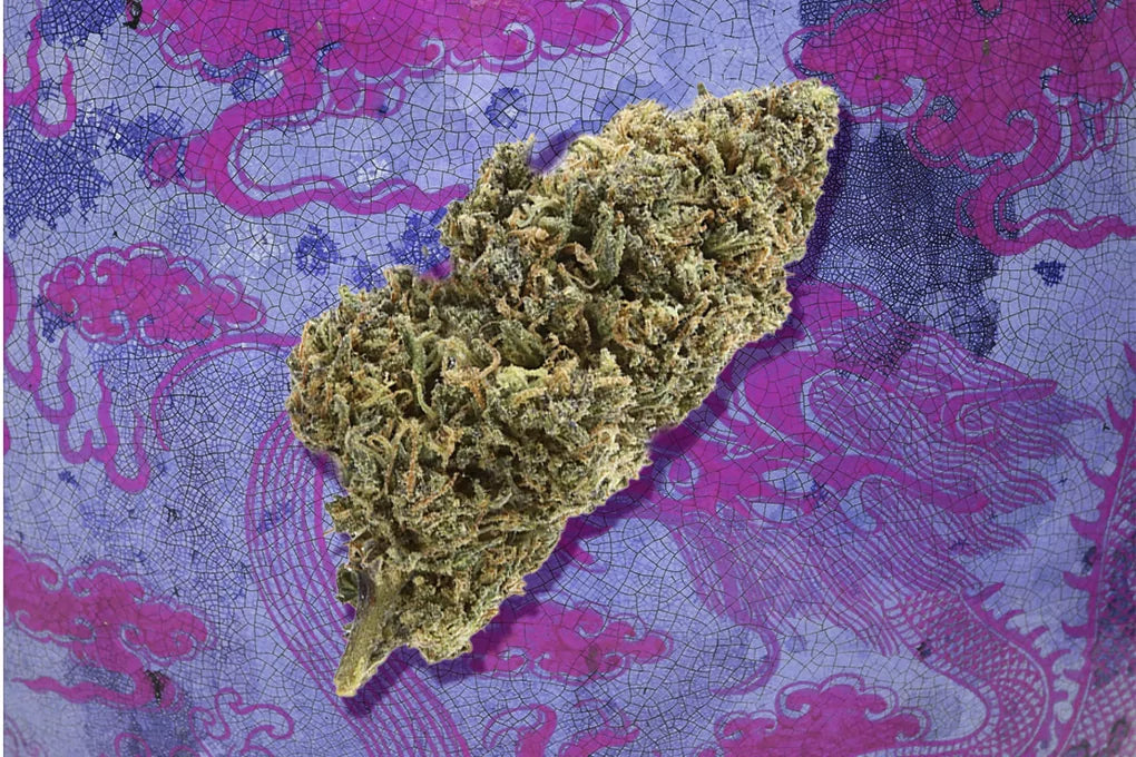 a nugget of Dojo Kush strain floats in front of a purple background of dragons and clouds
