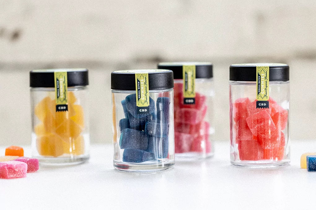 Four jars of Botany Farms Delta 8 THC gummies sit atop a countertop against a blurred background.