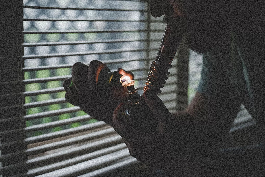A man smokes cannabis from a glass bubbler.