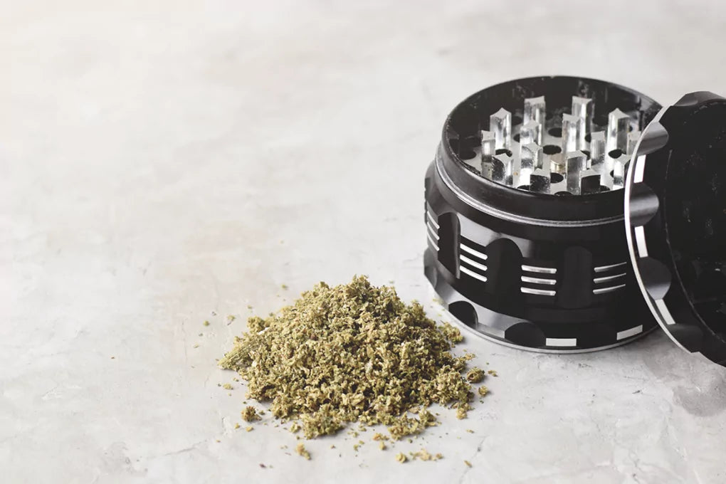 Dry kief sits in a pile next to a black weed grinder
