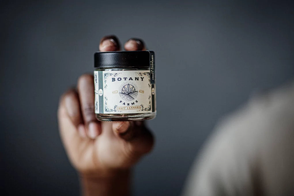 A person holds up a jar of CBD crumble