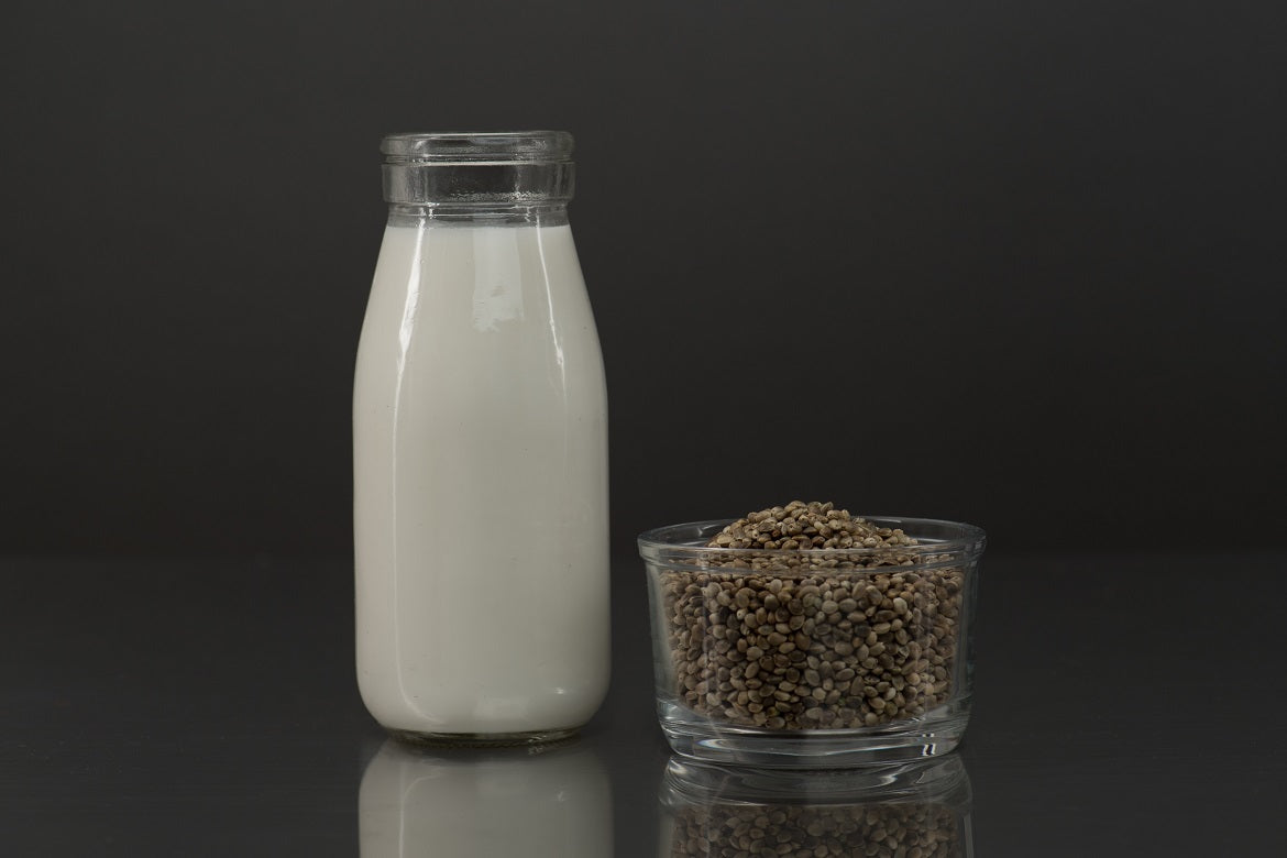 Glass of hemp milk next to a cup of hemp seeds