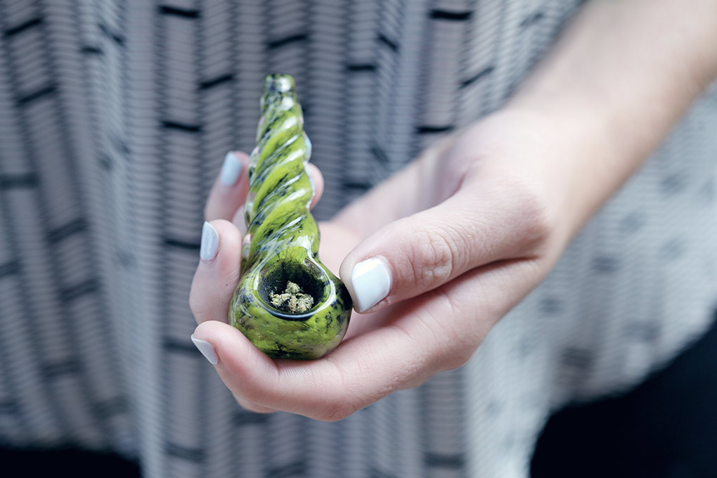 A woman is holding a vape pen in her hand