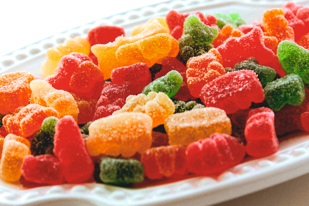 Assorted colorful gummies arranged on a plate with gentle light highlighting their textures and hues