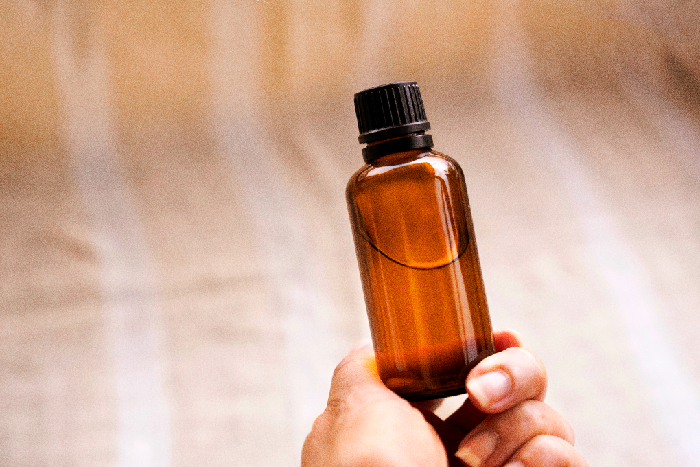 Hand holding tincture with liquid against hazy background