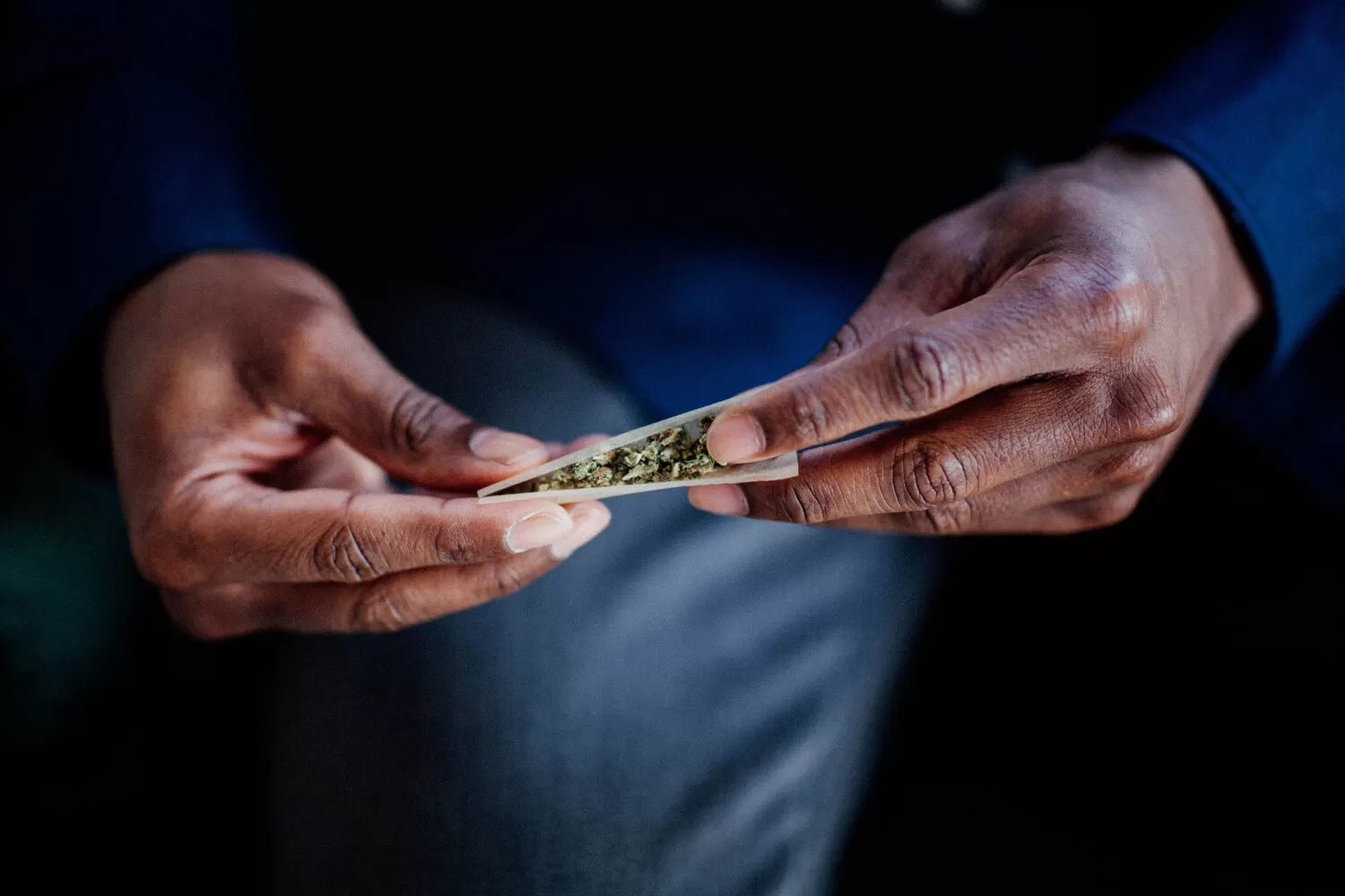 A man rolling a hemp flower joint