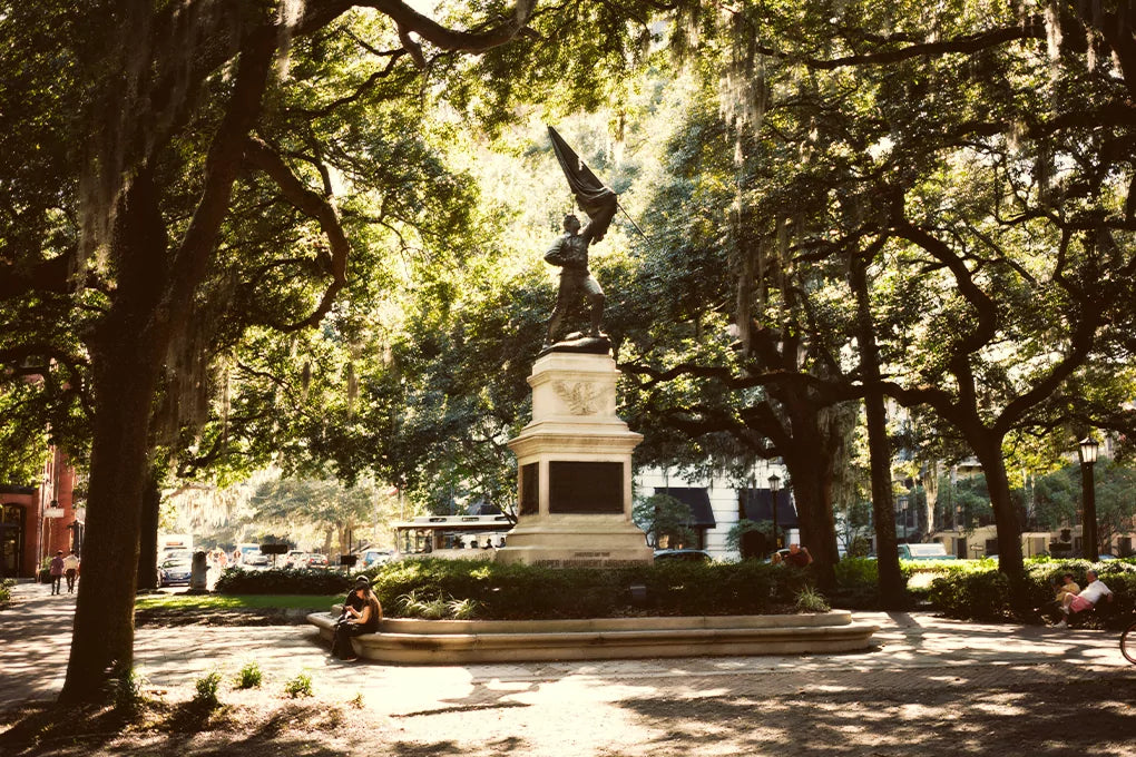 The statue of William Jasper in Madison Square, Savannah on a sunny day with trees and a few people around