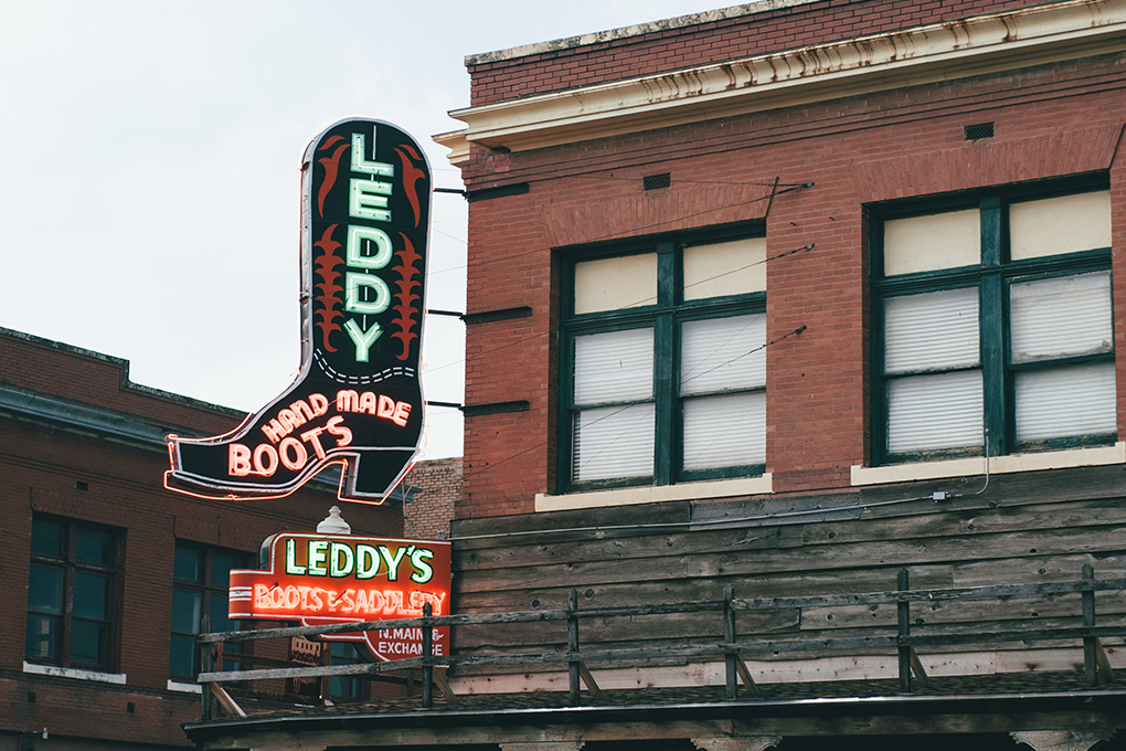 Vibrant red building in Texas with a neon sign that reads 'LEDDY HAND MADE BOOT' showcasing exquisite craftsmanship