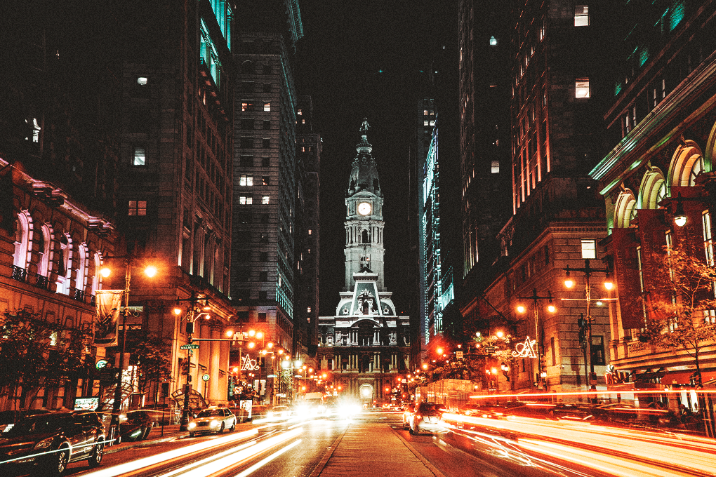 Night view of Philadelphia Street with William Penn statue, bustling traffic, and glowing streetlights in Pennsylvania