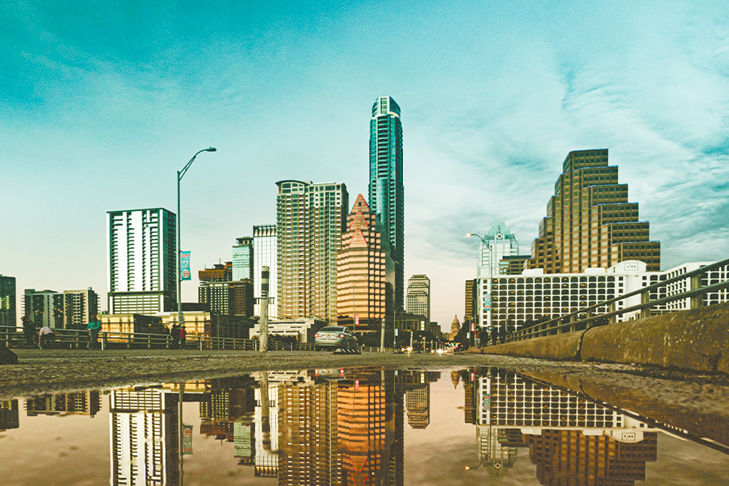 Texas City skyline with buildings, people walking and cars on a road, with water present - bustling city scene on a sunny day