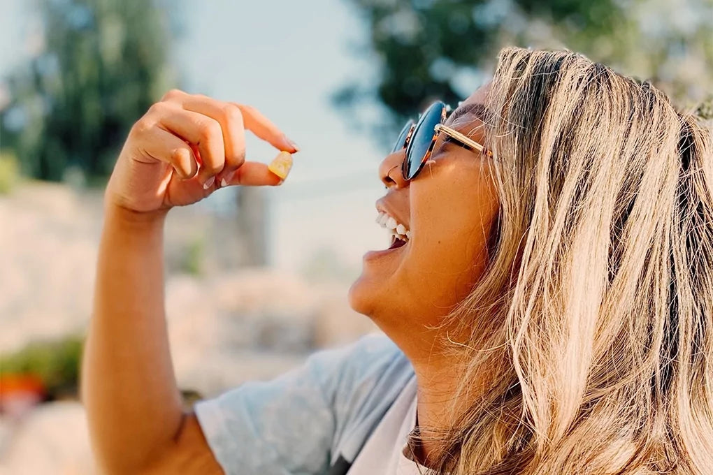 A woman holds a delta 8 gummy candy up to her mouth.