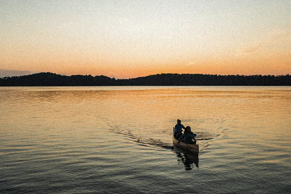 A couple of people riding in a canoe at sunset on a lake in Minnesota.