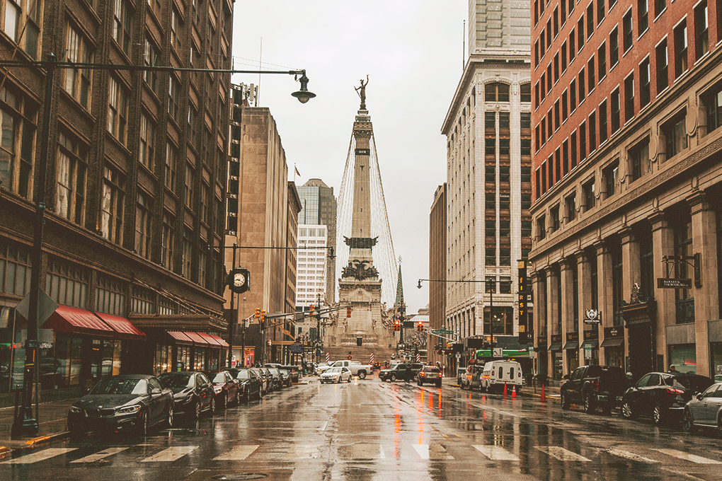 A picture of the city of Indianapolis, with buildings, cars, and a prominent statue