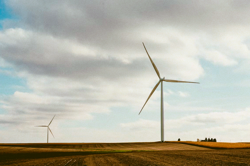 A view of an open field in Iowa with wind turbines in the distance.