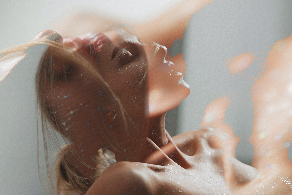 A woman reclines with her head tilted back, eyes closed, in a state of relaxation while enjoying libido gummies