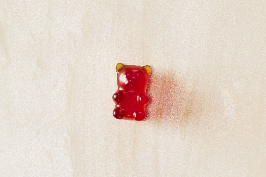 A red bear-shaped gummy resting on a white surface