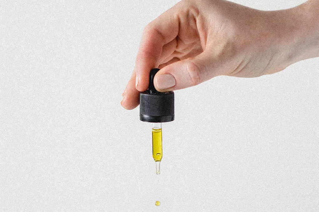 Hand holding dropper with yellow liquid on white background