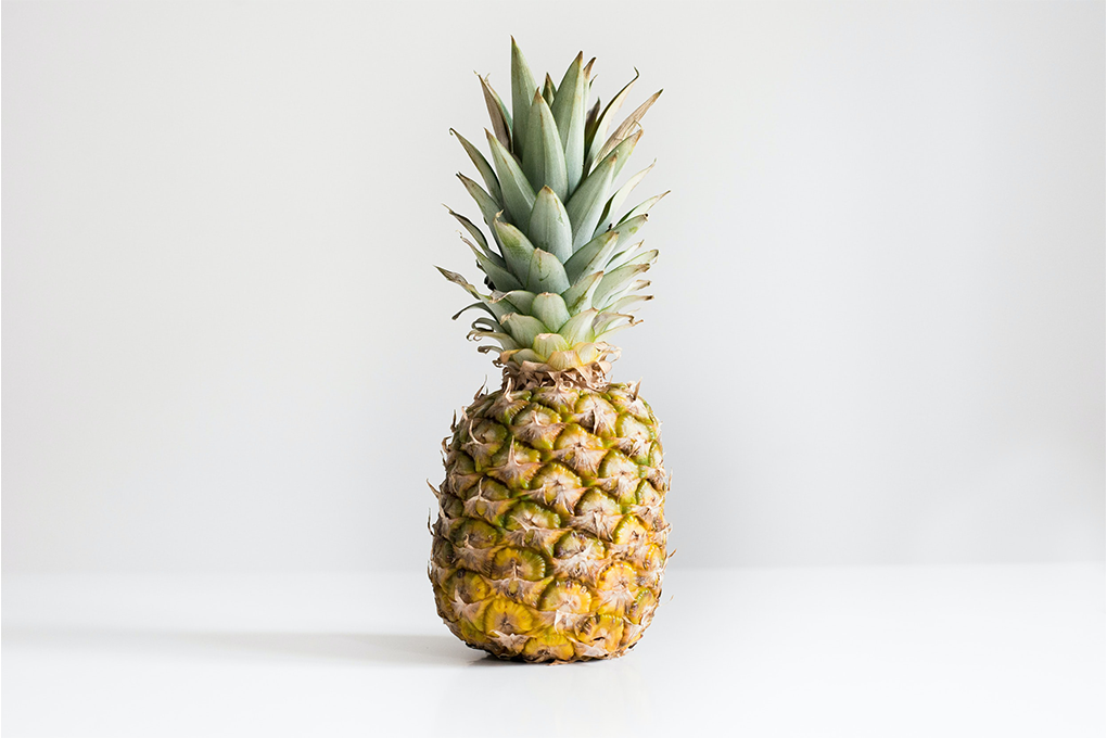 A vibrant pineapple resting on a white surface, evoking tropical freshness and natural beauty