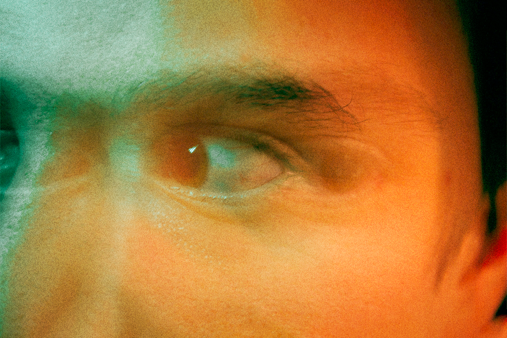 Frightened man with fearful expression, eyes wide in distress, surrounded by green and orange lights