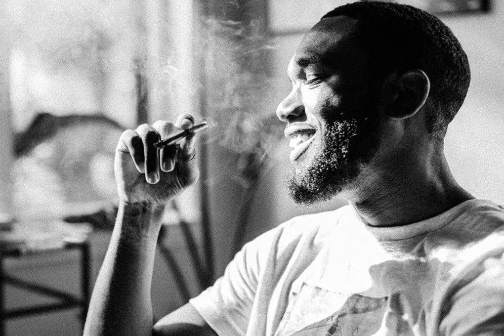 A man smiles as he smokes a joint which contains Cannabichromene.