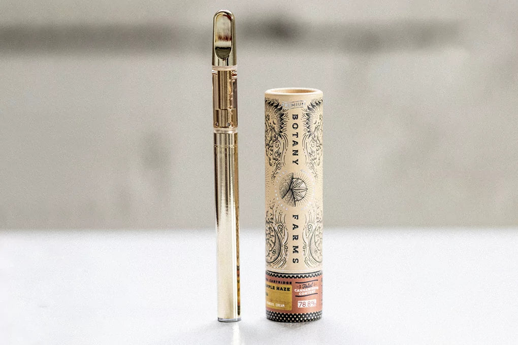 A Botany Farms CBD vape sits next to a Botany Farms pre roll CBD tube on a counter.