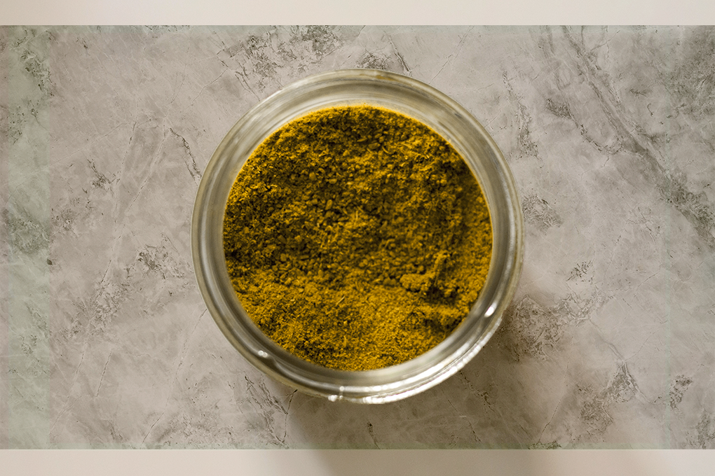 Yellow kief weed in a glass bowl on white surface