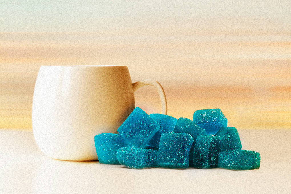 A white cup with blue cube-shaped gummies placed on a white surface