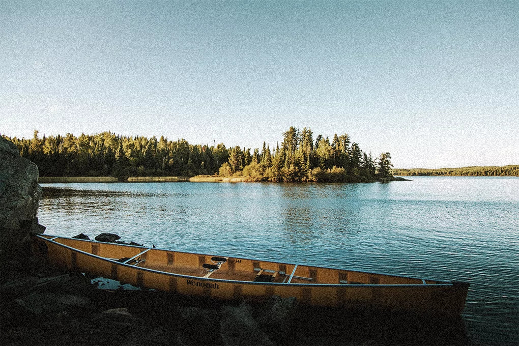 A view of a river in Minnesota with a canoe in the foreground and trees in the background.