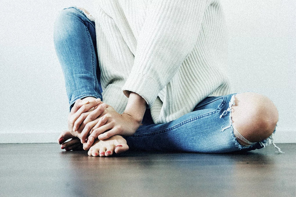 The lower half of a person is seen clutches their feet in their hands in pain. What are the best CBD strains for inflammation?
