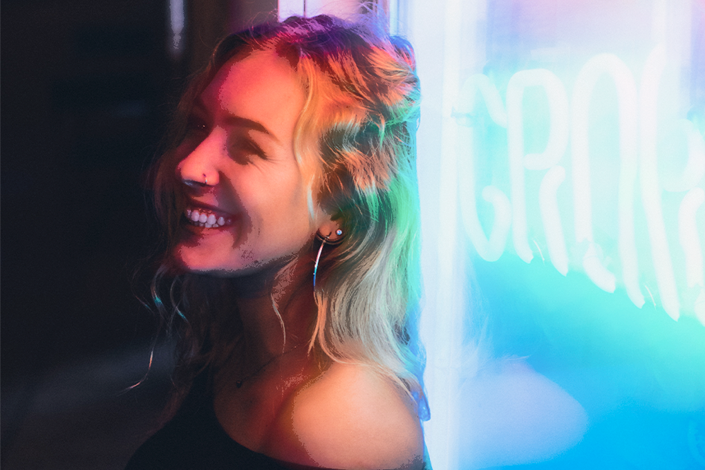 Radiant woman with a joyful smile, warm reddish light illuminating her face, while cool bluish light enhances her captivating hair