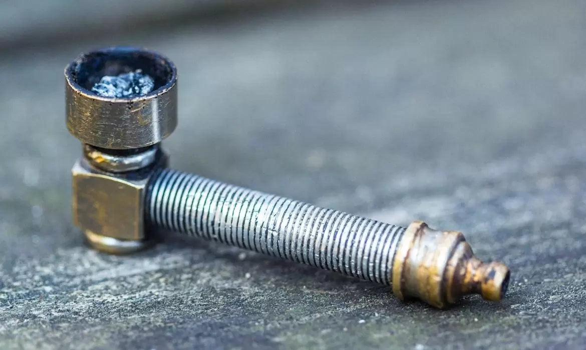 Used metal weed pipe sits on top of a wooden table.